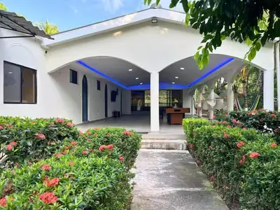 a white house with a porch and some flowers at Pool • Fire Pit • Game Room • Resort Access in Los Cóbanos