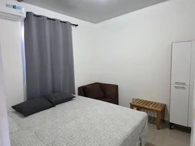 a bedroom with a bed with a gray curtain and a chair at Casa Nueva San Miguel in San Miguel