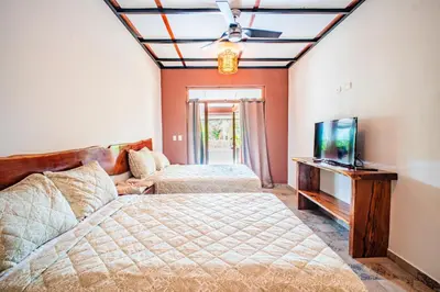 a bedroom with two beds and a flat screen tv at Casa Las Flores in El Cuco