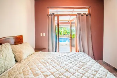 a bedroom with a bed and a sliding glass door at Casa Las Flores in El Cuco
