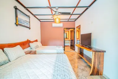 a bedroom with two beds and a flat screen tv at Casa Las Flores in El Cuco