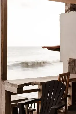 a wooden table and chair with a view of the ocean at AST Surf Hotel in La Libertad