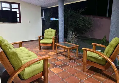 a patio with chairs and a table and a tv at Quinta Hojas de Mar - Frente al Mar en Playa Las Hojas in El Rosario