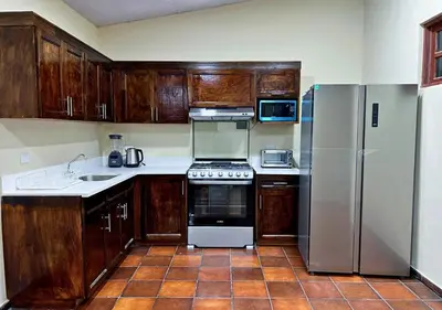 a kitchen with wooden cabinets and stainless steel appliances at Quinta Hojas de Mar - Frente al Mar en Playa Las Hojas in El Rosario