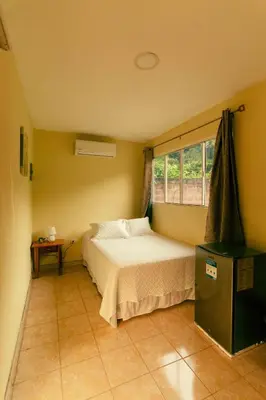 a small bedroom with a bed and a window at Hotel Castillo Blanco in El Zonte