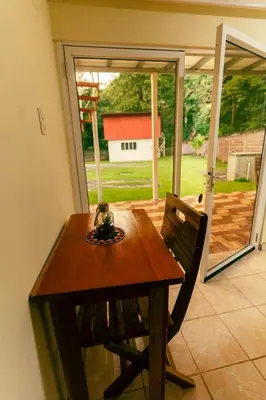a wooden table and chair in front of a sliding glass door at Hotel Castillo Blanco in El Zonte