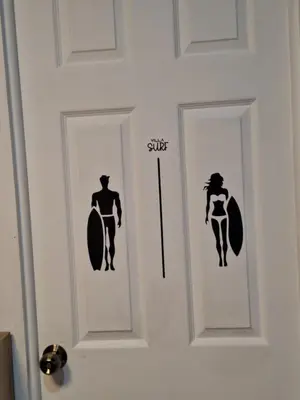 a door with two doors with a man and a woman with a surfboard at Villa Sunzal Surf Retreat' in La Libertad
