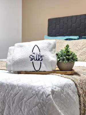 a white towel sitting on a bed with a plant at Villa Sunzal Surf Retreat' in La Libertad