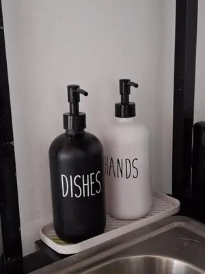 two black and white bottles on a shelf next to a sink at Villa Sunzal Surf Retreat' in La Libertad