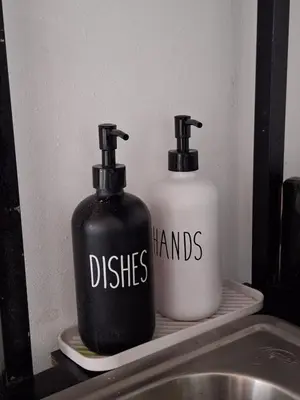 two black and white bottles on a shelf next to a sink at Villa Surf Retreat in La Libertad