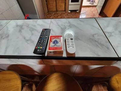 a table with two remote controls and a book on it at Linda casa con garaje en la majada