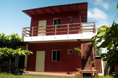 a red house with a balcony on top of it at Beachfront Hotel near International Airport in Las Hojas