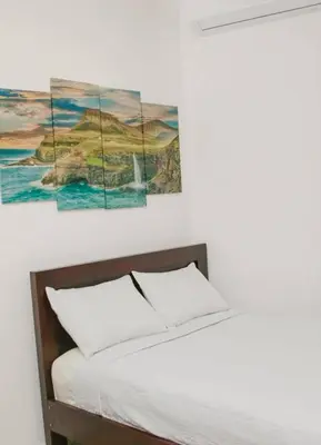 a bedroom with a bed with three paintings on the wall at Mar Adentro San Blas in Playa San Blas