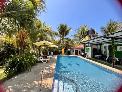 a swimming pool with palm trees and a house at Mar Adentro San Blas in Playa San Blas