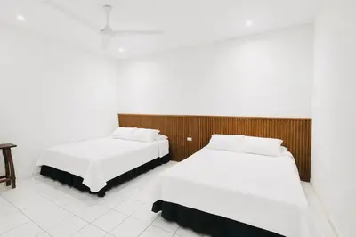 two beds in a room with white walls at Hotel Raíces Ataco in Concepción de Ataco