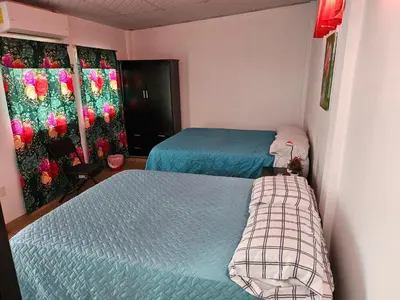 a bedroom with two beds and a window with flowers at El hostal de Uriel in Izalco