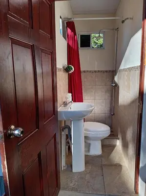 a bathroom with a sink and a toilet and a door at Zacatecoluca House Hostel 2 nivel in Zacatecoluca
