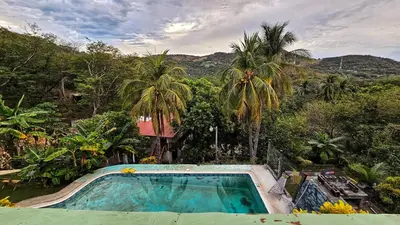 a swimming pool in a resort with palm trees at 4 Amigos El Zonte in ChiltiupÃ¡n
