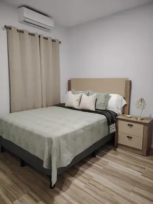 a bedroom with a bed and a nightstand with a bed sidx sidx at Veraneras House, your home in Santa Ana, El Salvador in Santa Ana