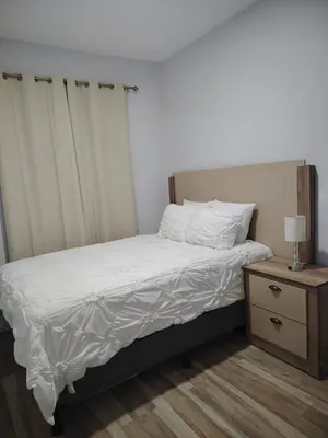 a bed with white sheets and a nightstand with a lamp at Veraneras House, your home in Santa Ana, El Salvador in Santa Ana