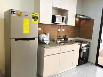 a kitchen with a refrigerator and a microwave at Cozy house 5 minutes from the airport in Las Flores