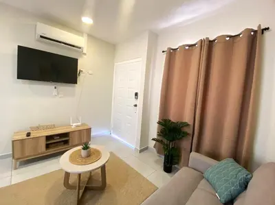 a living room with a couch and a tv at Cozy house 5 minutes from the airport in Las Flores