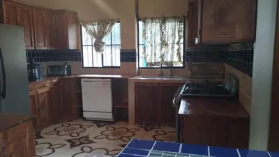 a kitchen with wooden cabinets and a stove top oven at Ahuachapán Getaway