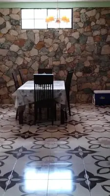 a table and chairs in a room with a stone wall at Ahuachapán Getaway