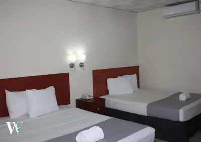 a hotel room with two beds with white sheets at Hotel Windsor Plaza in San Salvador