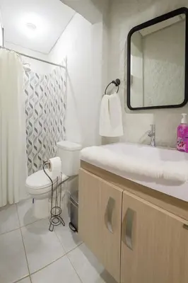 a bathroom with a sink and a toilet and a mirror at Apto en Santa Ana con AC in Santa Ana