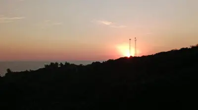 a sunset on a hill with the sun setting over the ocean at Kchimbon rooms best place stay view all Zonte in El Zonte