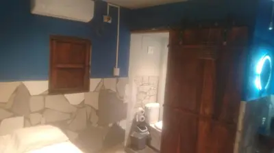 a bathroom with a bed and a wooden cabinet at Kchimbon rooms best place stay view all Zonte in El Zonte