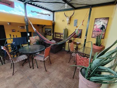 a restaurant with tables and chairs and a hammock at Rooms libertad in San Salvador
