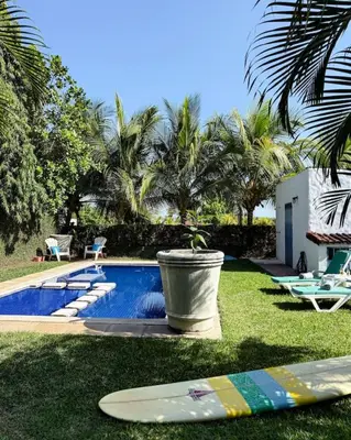 a pool with a potted plant and surfboards on the grass at Casa Cielo in La Libertad