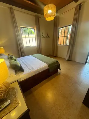 a bedroom with a bed and a table and windows at Dos Palmas in El Sunzal