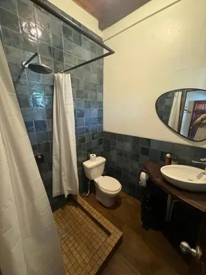 a bathroom with a toilet and a sink and a mirror at Dos Palmas in El Sunzal