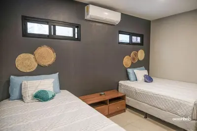 a bedroom with two beds and two windows at Cala los Mangos in Tamanique