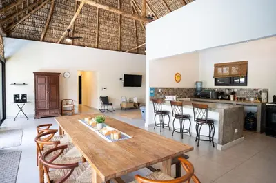 a dining room and kitchen with a wooden table and chairs at Cala los Mangos in Tamanique