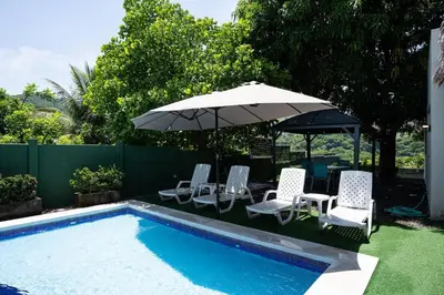 a group of chairs and an umbrella next to a pool at Cala los Mangos in Tamanique