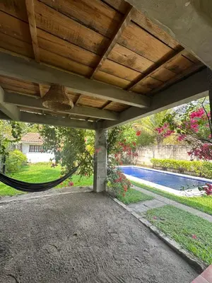 a hammock under a porch with a swimming pool at Casa Aquetzalli in San Salvador