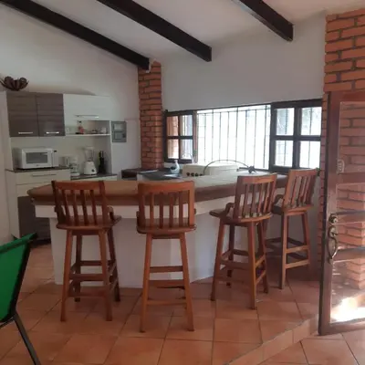 a kitchen with four wooden bar stools and a counter at Casa Aquetzalli in San Salvador