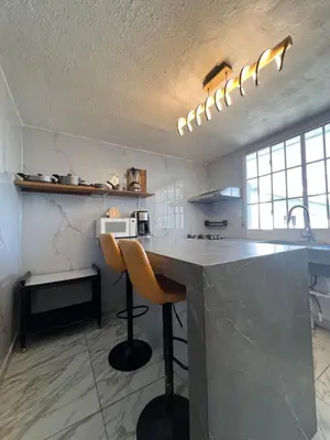 a kitchen with a counter with two chairs in it at Villa Napoli Apartment Suites in Santa Ana