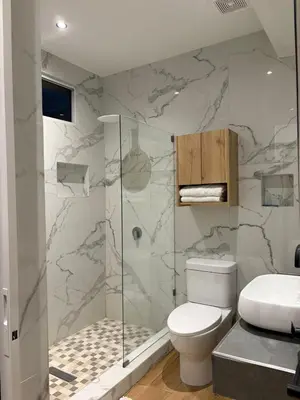 a bathroom with a toilet and a glass shower at Villa Napoli Apartment Suites in Santa Ana