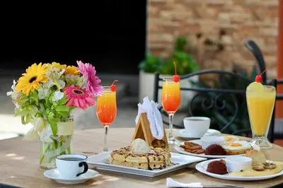 a table with plates of food and flowers and drinks at Villa Napoli Apartment Suites in Santa Ana