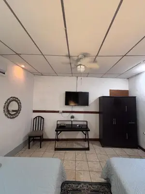 a room with a tv and a table and a couch at Villa Napoli Apartment Suites in Santa Ana
