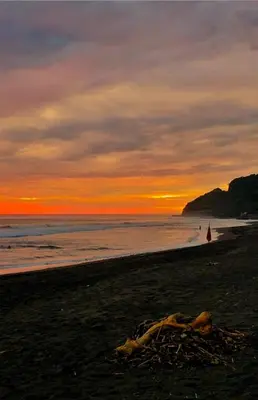 a beach with a person in the water at sunset at Sea Garden Mizata in Las Piedras