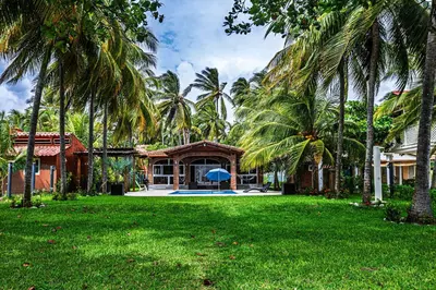 a house with palm trees in front of a yard at Rancho San Jose - Barra De Santiago in Barra de Santiago