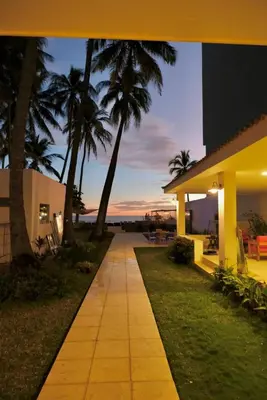 a walkway in front of a house with palm trees at Casa Origen El Zonte in El Zonte