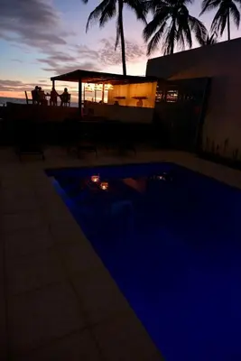 a night view of a swimming pool with a group of people at Casa Origen El Zonte in El Zonte