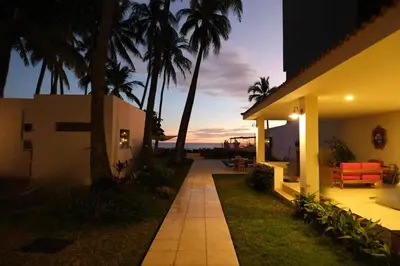 a house with a pathway next to a building with palm trees at Casa Origen El Zonte in El Zonte